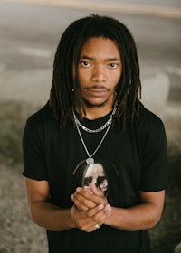 a young man with dreadlocks posing for a photo